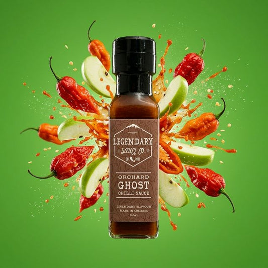 Bottle of Legendary Sauce Co. Orchard Ghost Chilli Sauce with ghost peppers and apples on a green background