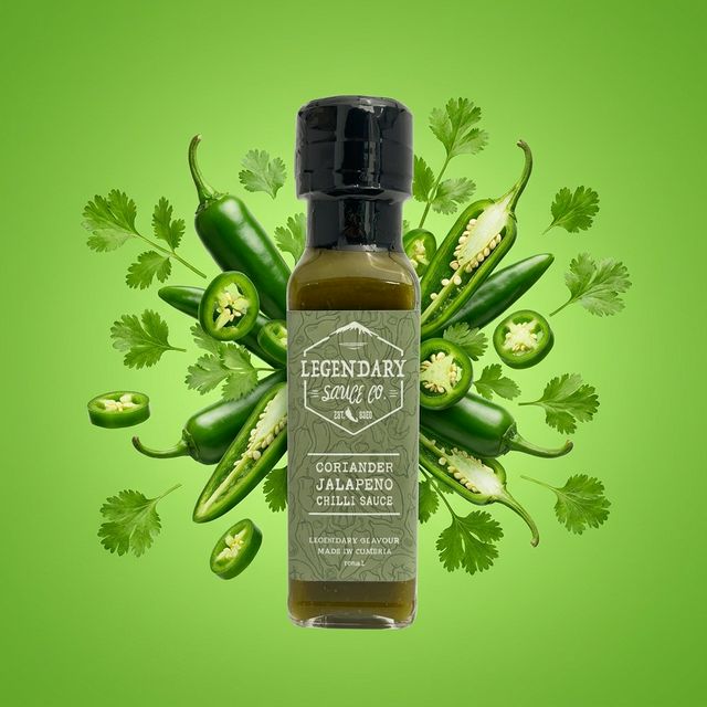 Bottle of Legendary Sauce Co. Coriander Jalapeno Chilli Sauce surrounded by jalapenos and cilantro on a green background