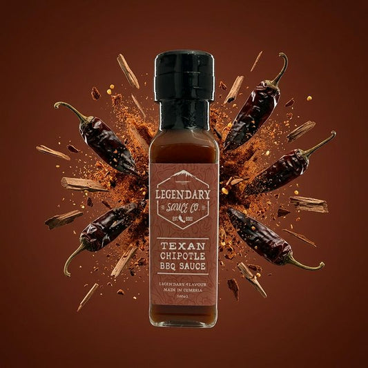 Bottle of Legendary Sauce Co. Texan Chipotle BBQ Sauce surrounded by chili peppers on a brown background